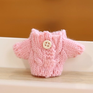 Detailed view of pink knitted doll cardigan with cable stitch and wood buttons