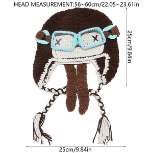 Detail of pilot style knit hat with goggles and braided tassels on white background