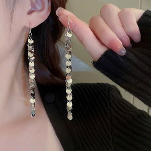 Detail of silver leaf sequin tassel earrings on model with high gloss metal finish
