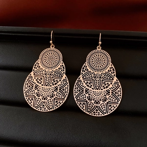 Macro shot of rose gold filigree drop earrings with intricate hollow floral patterns
