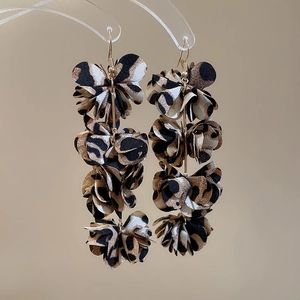Detail of leopard print fabric flower tassel drop earrings on acrylic jewelry display
