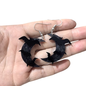Acrylic black bat and moon halloween earrings on silver hooks held by hand