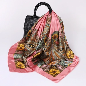 Close-up of pink paisley silk scarf draped on a black leather handbag for styling