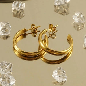Close-up of golden C-shaped hoop earrings with a matte brushed texture and pin closure