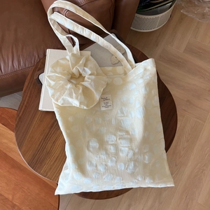 Detail of off-white bubble textured tote bag and matching scrunchie on a wooden table