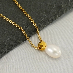 Detail of drop pearl necklace with hammered gold bead on silk and stone background