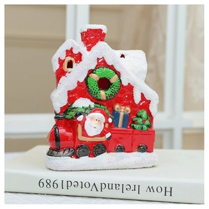 Detail of red ceramic Christmas house and train figurine with festive snow accents