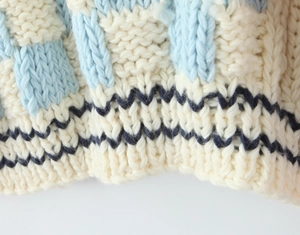 Vue macro détaillée de la texture tricotée à la main avec blocs tissés crème et bleu