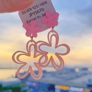 Detailed shot of pink flower earrings with silver posts and Japanese price tags