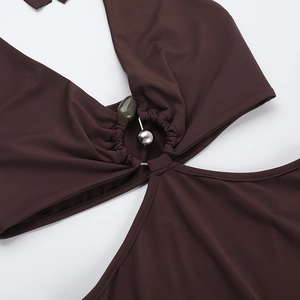 Détail du col en V avec perles dorées et pierres vertes sur une robe d'été marron chic