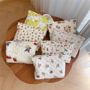 Flat lay of quilted cotton cosmetic bags with cute bear and floral prints on wooden table