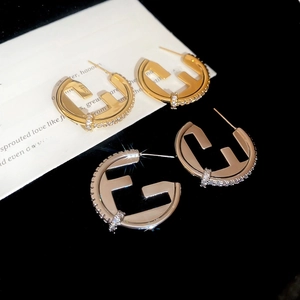 Close-up of gold and silver letter F stud earrings with sparkling cubic zirconia inlay