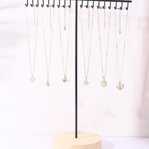 Golden iron necklace display stand with multiple heart and star pendant styles on wooden base