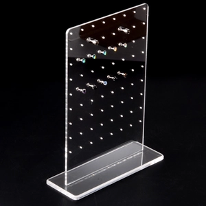 Macro detail of thick acrylic earring display stand with studs on black background