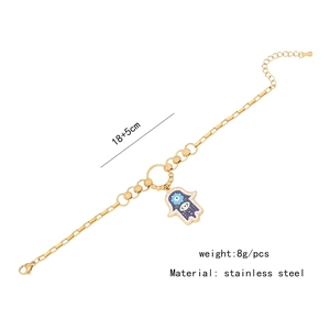 Macro detail of gold stainless steel Hamsa hand bracelet with blue enamel and crystal inlay
