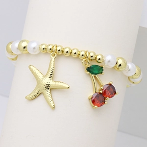 Close-up of golden starfish and crystal cherry charms on beaded pearl bracelet