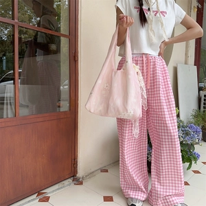 Outdoor shot showing pink floral embroidery tote bag size and fit on female model