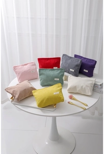 Group of colorful corduroy cosmetic bags displayed with makeup brushes and books