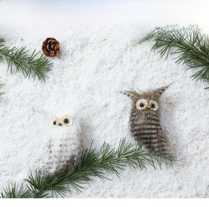 Charming owl Christmas tree decorations in white and brown fur on festive snow scenery