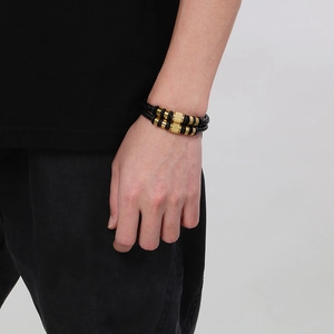 Vue détaillée du bracelet en cuir tressé noir avec des éléments en métal doré