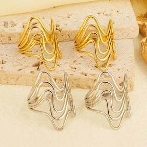 Detailed view of layered wavy open rings in gold and silver finishes on stone