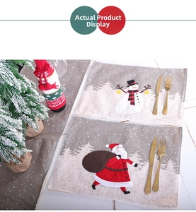 Close-up of Christmas placemats with Santa and Snowman prints and knitted wine bottle cover