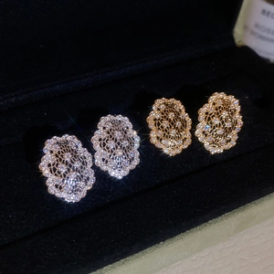 Gros plan de boucles d'oreilles ovales évidées en or et argent avec zircons sur velours noir