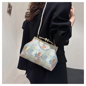 Detail of light blue silk embroidery handbag featuring floral patterns and a pearl strap