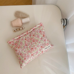 Detailed close-up of pink floral quilted makeup bag with simple wish label on white desk