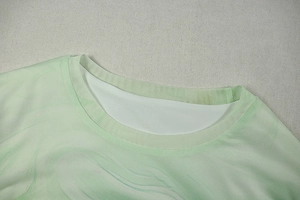 Detailed close-up of round neckline with mint green mesh fabric and print stitching