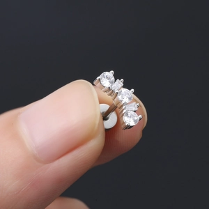 Dettaglio macro di orecchino a perno in acciaio argento con zirconi micro-incastonati