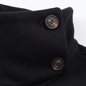 Gros plan sur un manteau noir en laine avec col montant et gros boutons de mode rétro