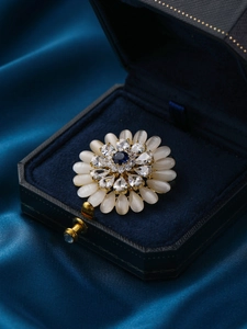 Detail of sunflower brooch with white opal petals and blue center in a velvet box