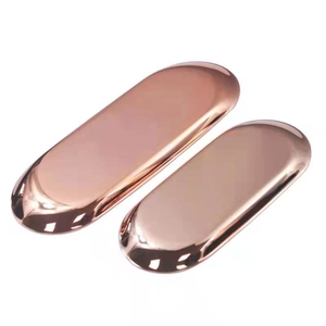 Detail of two oval rose gold stainless steel trays with mirror finish surface