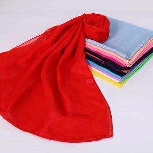 Foulard léger en mousseline rouge avec une pile d'écharpes de mode multicolores