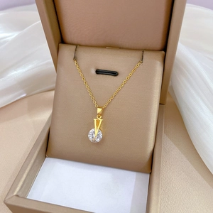 Macro detail of gold V-shaped pendant necklace with round zircon in a luxury jewelry box