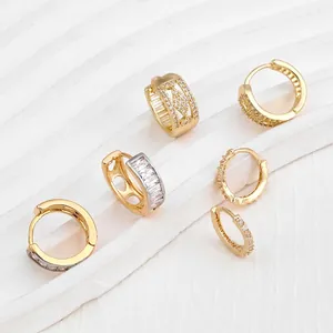 Elegant gold hollow hoop earrings with cubic zirconia stones on white wavy background