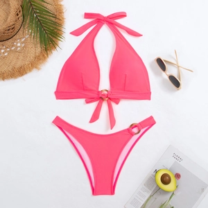 Flat lay of hot pink halter bikini with wooden rings and summer vacation accessories