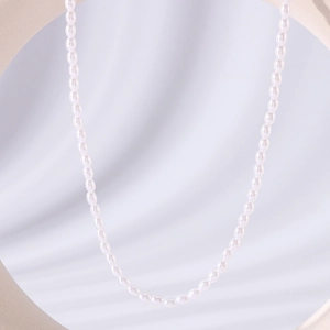 Elegant stainless steel necklace featuring natural white rice pearls on a wavy texture background
