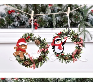 Close-up of felt gingerbread man and penguin wreath ornaments on a rustic jute rope