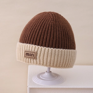 Close-up of dual-tone knit beanie with textured vertical stripes and brown leather min tag