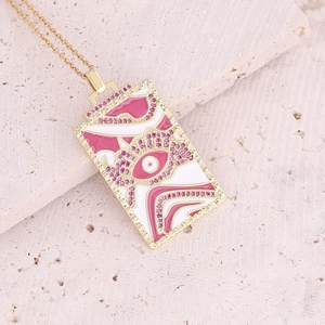 Macro view of gold rectangle necklace pendant with pink evil eye and rhinestone inlay