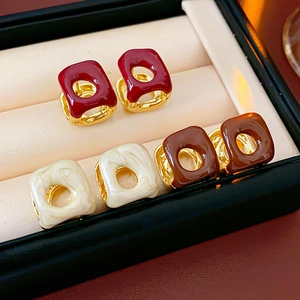 Detail view of square hollow enamel earrings in burgundy, brown and white marble