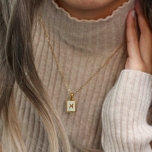 Gold Pisces constellation necklace with square white shell pendant on a model