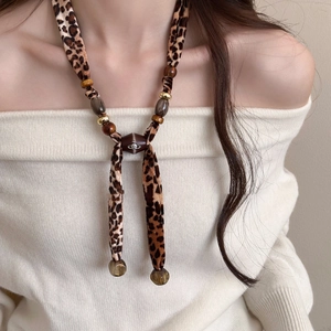 Detail of leopard print fabric necklace with star beads and metallic orb pendant