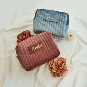 Detail of personalized velvet cosmetic bags with ribbed texture and gold name patches
