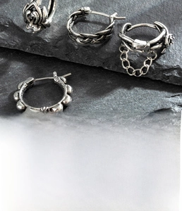 Macro shot of silver titanium steel earrings with cubic zirconia and woven textures