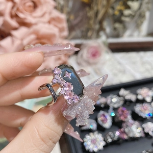 Macro detail of silver ring with Asscher cut pink zircon and bow on manicured hand