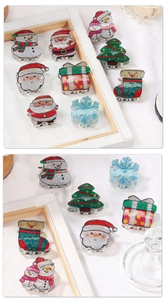 Macro detail of Christmas hair claws with glittery Santa, snowman and tree designs