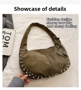 Detail shot of olive suede crescent bag featuring silver studs and heart pendant charm